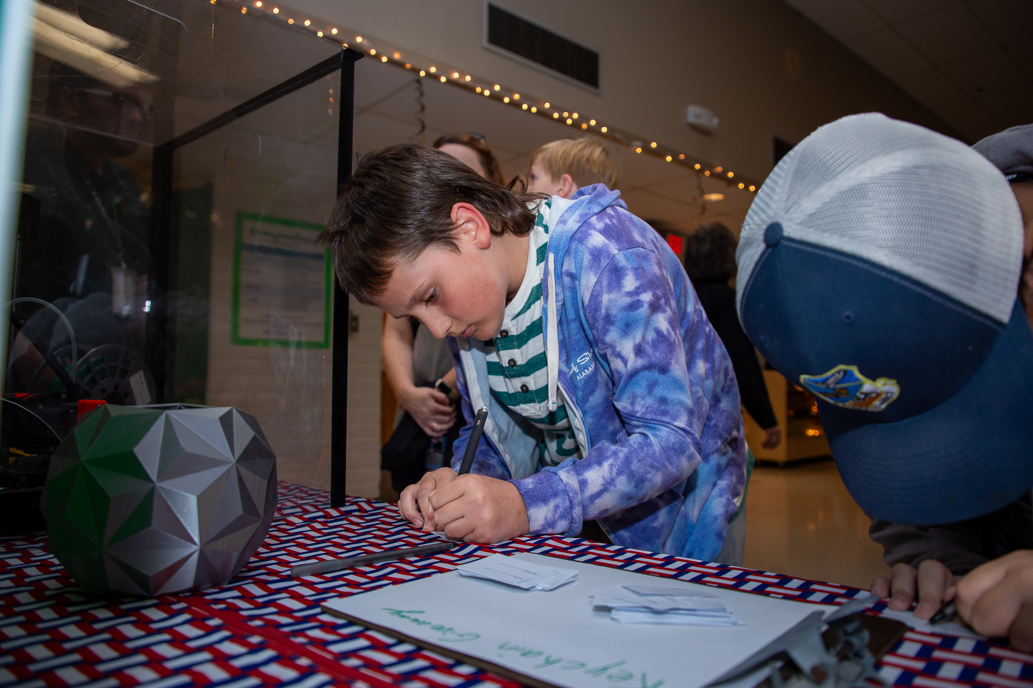 Two boys hunch over a table writing notes