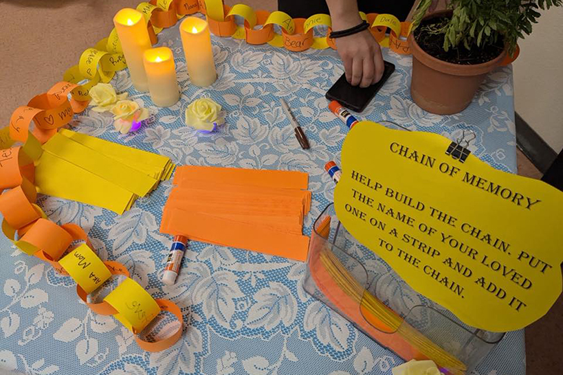 An orange and yellow paper chain around a table decorated with candles and plants