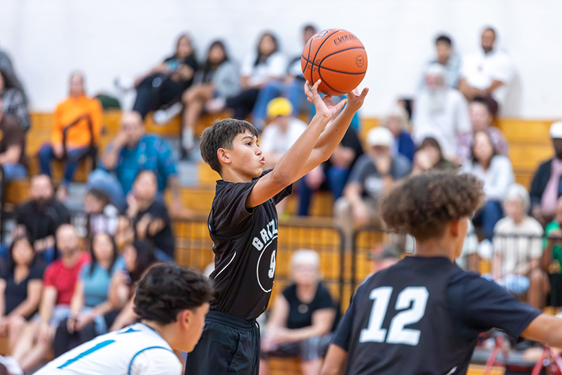 A boy tosses the basketball up