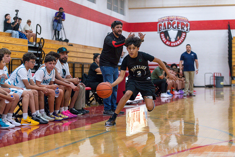 A boy dribbles the basketball down the court