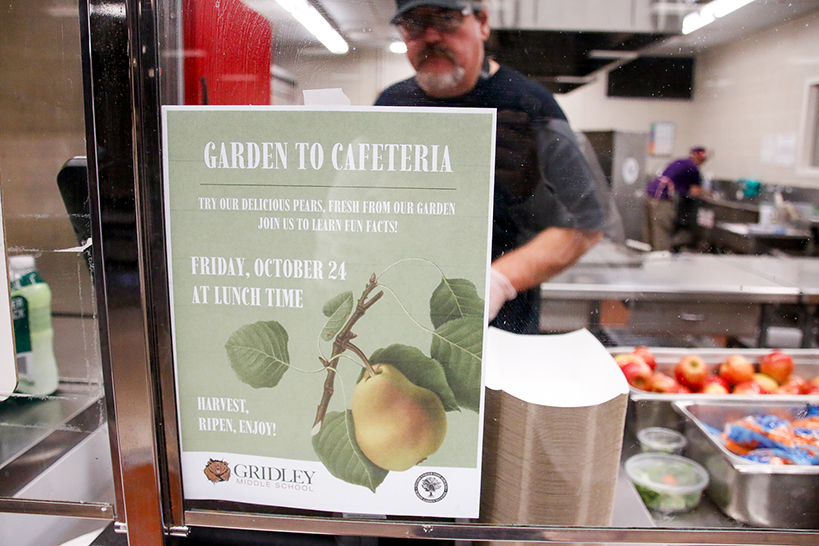A flyer advertising the Garden to Cafeteria event on the cafeteria window, with a man working inside